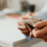 Woman with manicured nails holding a wad of cash of cash bill against blurred background. Photo by Photo By: Kaboompics.com: