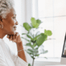 Mature Black woman working on Pinterest at her computer in a light, modern home office, researching ideas and content strategy in a calm, minimalist workspace. She is searching for pinterest hacks